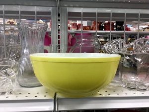 A greenish yellow bowl on a Goodwill shelf