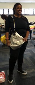 A woman in black pants and black shirt with a large silver purse