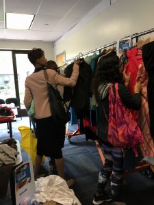 A picture of the DCGF Swap attendees looking through the items that are being swapped. Most of the items are clothing and are placed on tables and on racks