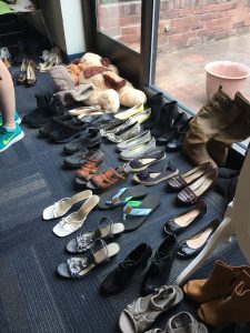 A picture with dozens of pairs of different kinds of shoes in front of a window