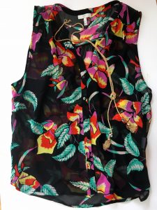 A picture of a sleeveless, black, button up, blouse with a floral patterm