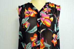 A picture of a sleeveless, black, button up, blouse with a floral patterm