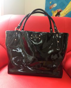 A picture of a black Kate Spade purse on a red chair