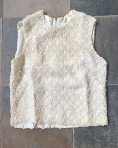 A cream colored sequin sleeveless shirt