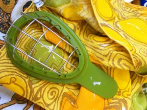 An avocado cuber on top of A couple of yellow napkins with a faded vintage yellow, green, and orange pattern