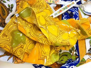 A couple of yellow napkins with a faded vintage yellow, green, and orange pattern