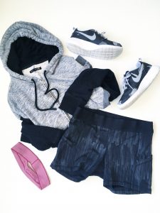 A picture of four items: a size medium, comfy, soft gray and black, paneled hoodie by Rag and Boone, stretchy, elastic, black Lululemon fitness mini running shorts in a size 8, a pair of Nike, grey, black, and white monochromatic running shoes, and a pink headband