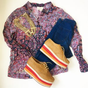 A picture of a pattern-mixing, artistic, party button-down by designer Nicole Miller Atelier in a size medium, a pair of blue skinny jeans, multi-colored, platformed, oxford cut shoes, and a five cord gold necklace