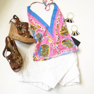 A picture of a pink holter top with beach prints on it; leather strap, cork wedge sandals, a white skort, and a pair of hoop earrings that have black and white tassels on them 