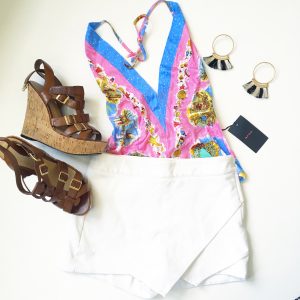 A picture of a pink holter top with beach prints on it; leather strap, cork wedge sandals, a white skort, and a pair of hoop earrings that have black and white tassels on them 