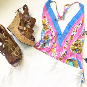 A picture of a pink holter top with beach prints on it; leather strap, cork wedge sandals, a white skort