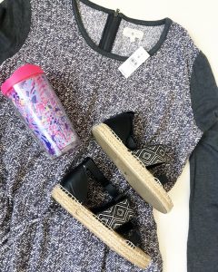 A close up of the dark gray and white, long-sleeved, patterned, Lou & Grey summer dress in a size large, a pink, purple, and light blue Lilly Pulitzer tumbler cup, and a pair of black and tan woman's sandals.