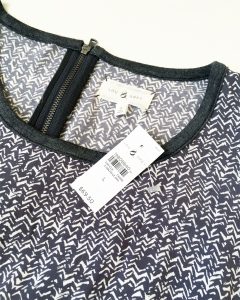 A picture of the tag of the dark gray and white, long-sleeved, patterned, Lou & Grey summer dress in a size large. The tag says the dress originally sold for $69.50