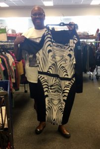 A picture of an African American woman holding up a black and white stripped dress