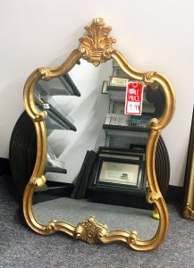 A wall mirror with an ornate, gold, boarder frame