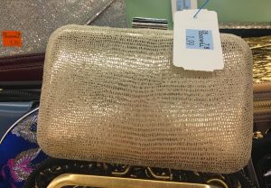 A picture of a gold, almost snake skin rigid clutch purse. It has a Goodwill tag on it that states it is $1.99