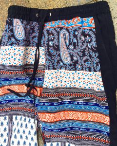 A pair of ornately patterned Topshop pants. They have the colors orange, blue, navy, light blue, and white. They have a drawstring at the top.