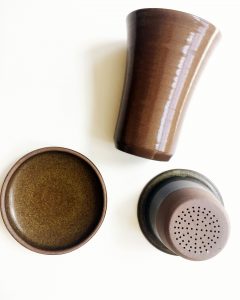 A picture of various pieces of a brown, ceramic, tea infuser