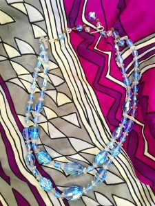 A necklace that is a small blue choker made of blue transparent stones