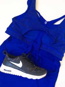 Ultramarine blue and black striped, sleeveless, Lululemon workout top with a black Nike workout sneaker on top of it.