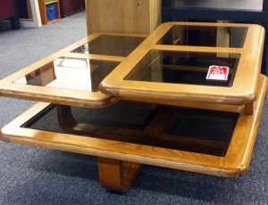 A layered wooden coffee table with square glass paneling 