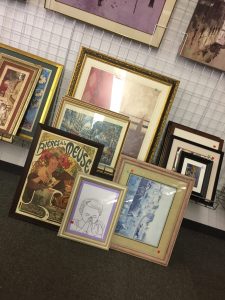 A picture of various pictures and frames at a Goodwill store