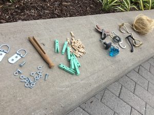 Different materials needed for the DIY frames project. These include eye hooks, different kinds of clothing clips and pins, door knobs, hangers, screws, and nails