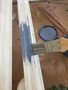 A picture of the close up of a paint brush painting a picture frame blue