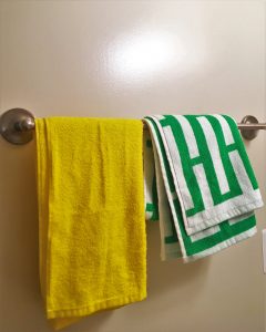 A picture of two shower towels. One is yellow and the other has a green and white pattern on it