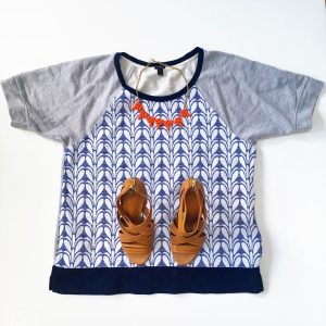 A picture of three items: a size large, quilted, blue and gray, patterned, baseball-style, short sleeved J Crew top, a pair of leather strap pump heels, and a salmon colored baulb necklace 