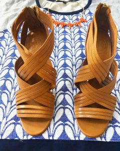 A picture of three items: a size large, quilted, blue and gray, patterned, baseball-style, short sleeved J Crew top, a pair of leather strap pump heels, and a salmon colored baulb necklace. A close up of the shoes