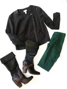 A picture of four items: a black moto jacket with leather patches in different places and a zipper, a pair of hunter green jeans, and a pair of black boots with brown leather straps and short heels