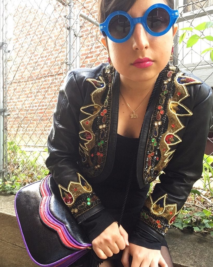 Carolyn models a vintage leather cross body bag, embellished faux leather jacket, and blue Lennon-style shades