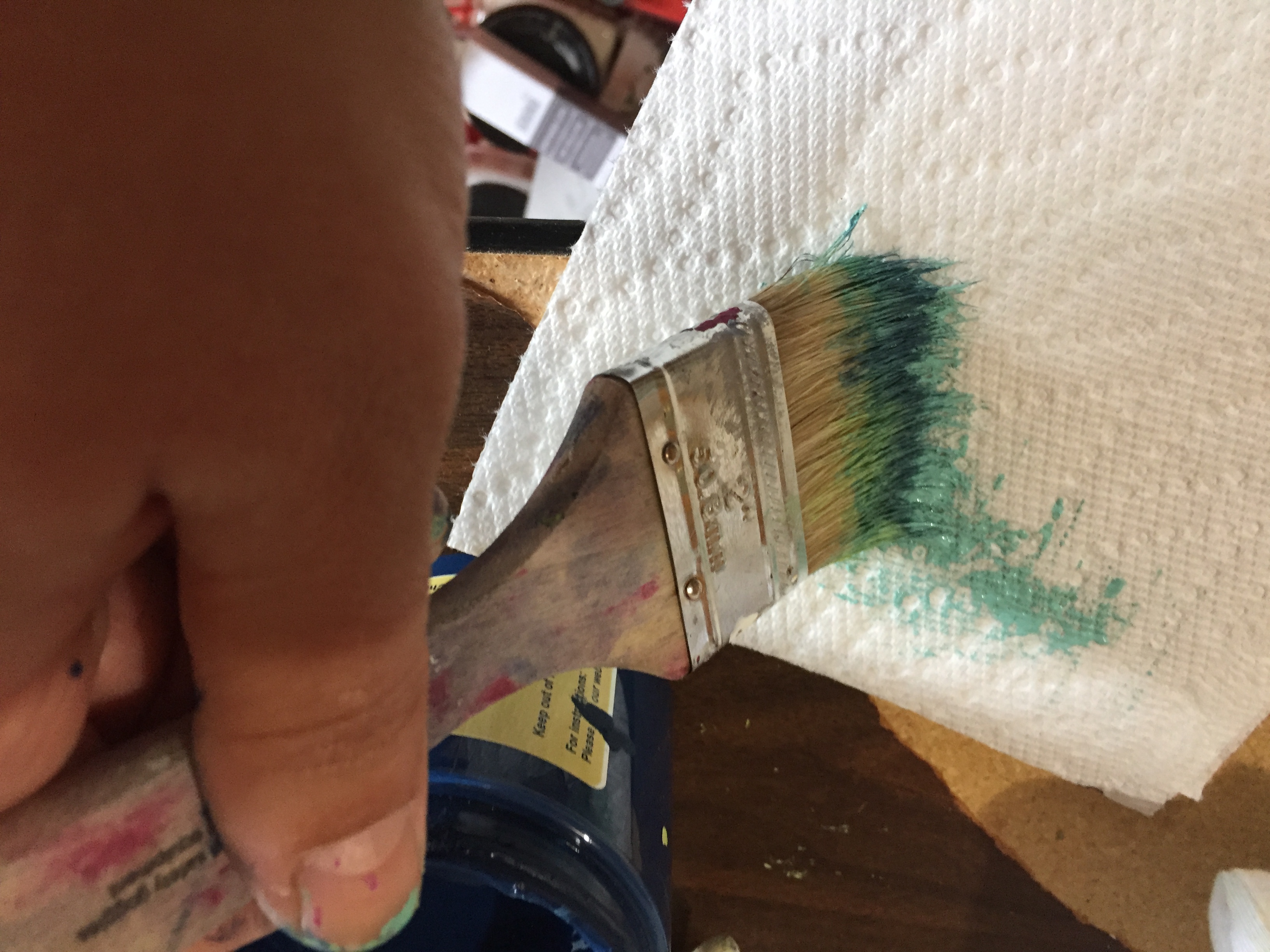 Courtney dabs the paint brush on a paper towel