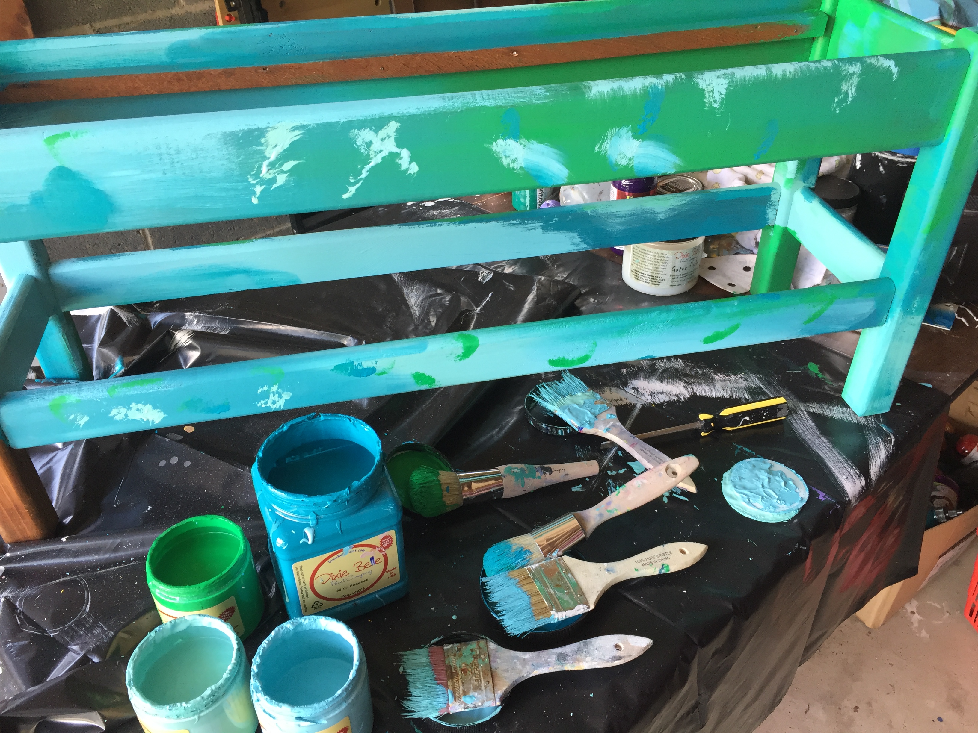 Courtney paints the bench several shades of blue as well as green