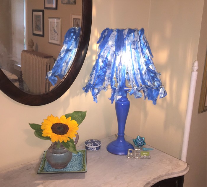 Tim displays a completed upcycled lamp in a room