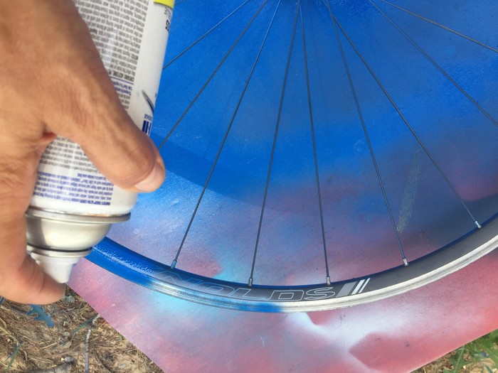 Tim spray paints the bicycle wheel blue 