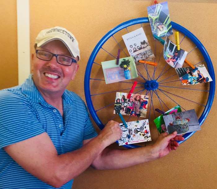 Tim posses with his completed blue bike wheel memo board 