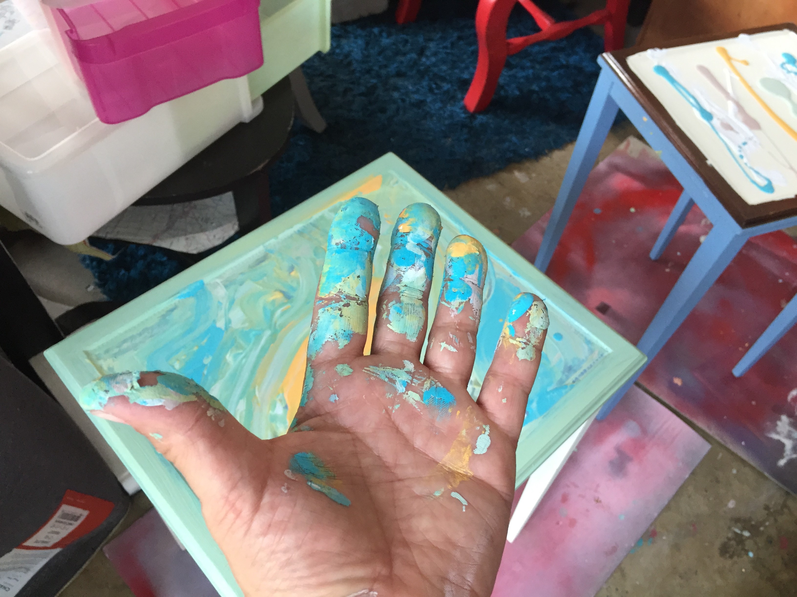 Tim's hand after touching up the paint job on a side table.