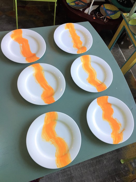 Tim paints an orange wave on each plate