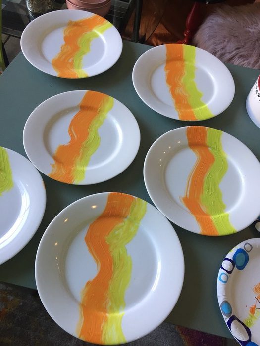 Tim paints an yellow wave on each plate