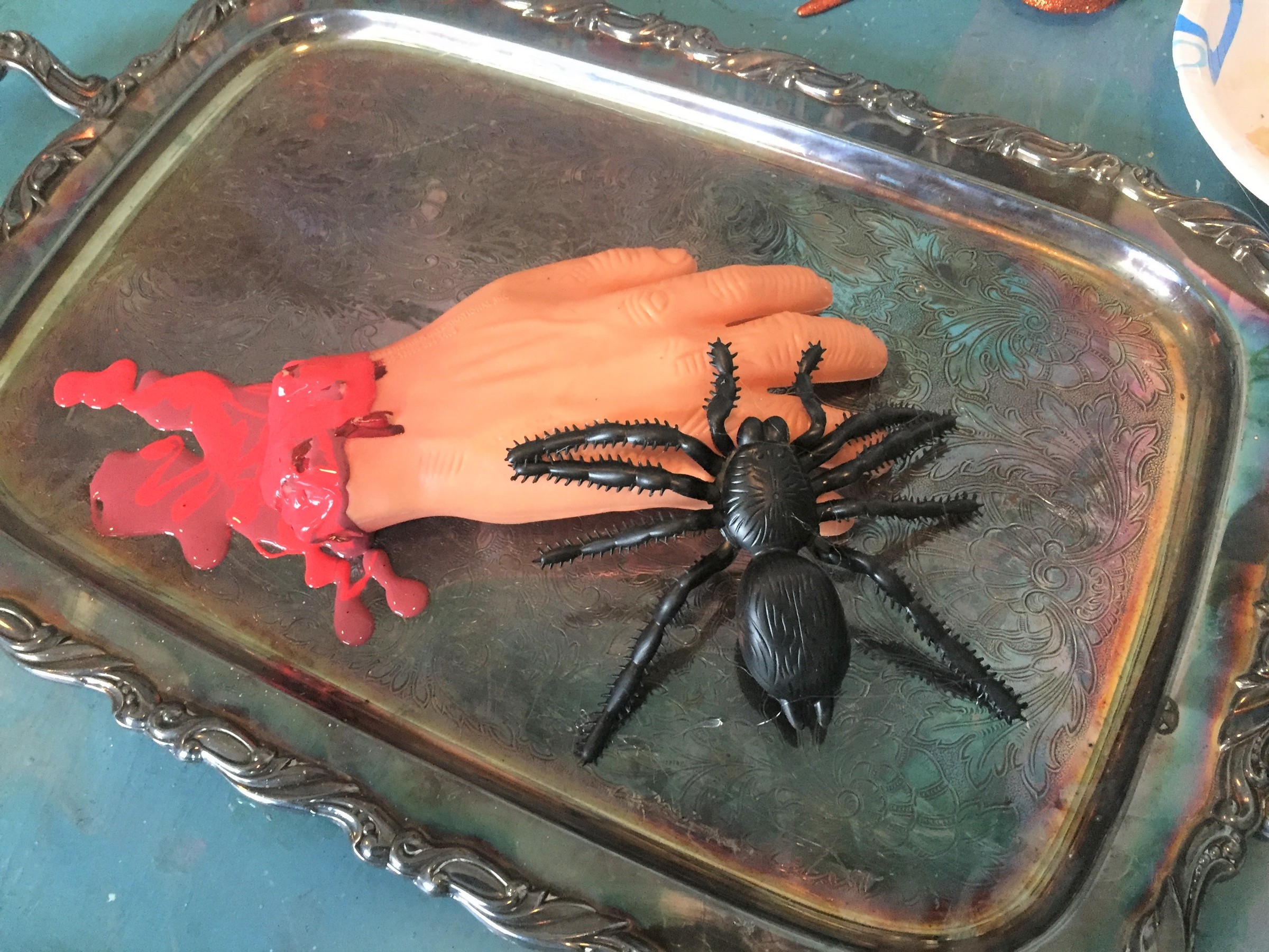 Tim glues a fake hand and spiders to a serving tray from Goodwill